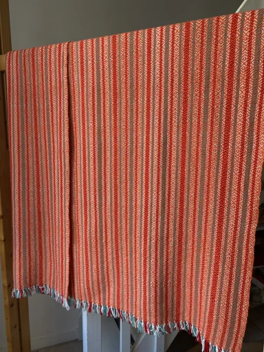 plaid suspendu : motif en bandeaux verticaux de vert, de rouge et d'écru sous la trame orange