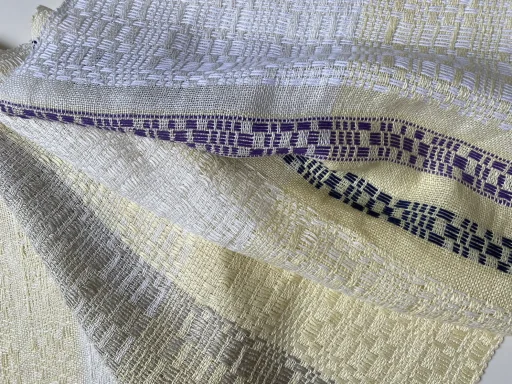 la souplesse et la brillance du tissu tissé en flotté en fil de lin jaune, blanc et gris non teinté et pour les frises en coton