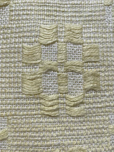 zoom sur le motif composé de deux groupes : un avec fil flotté long en couleur jaune clair et l'autre avec toile blanche
