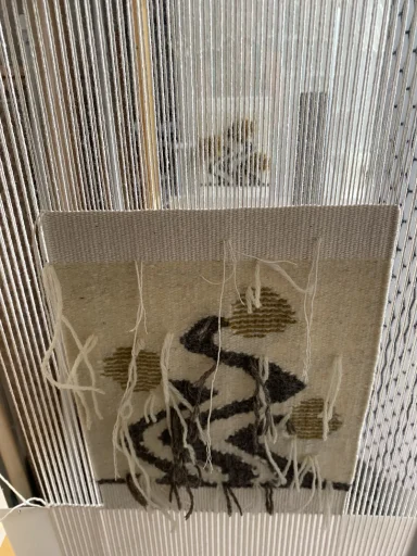 travail de tapisserie en cours devant un miroir : la partie tissée et chaîne de la partie non tissée 